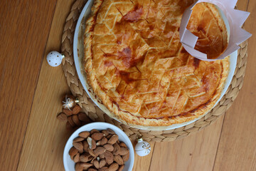 Galette des rois, traditional french cake with almond cream and festive decorations on wooden table. Epiphany cake