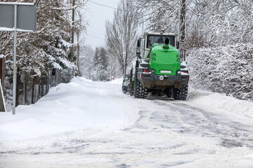 Tractor clears snow on road after heavy snowfall, road maintenance in winter season