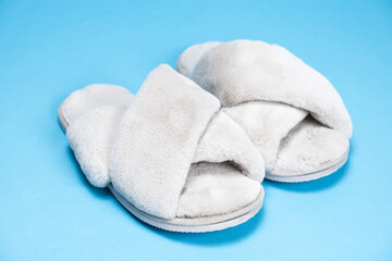 Modern stylish fluffy grey slippers on blue background