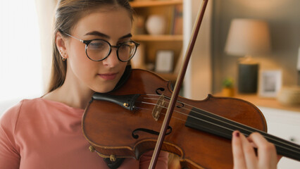 A teenage girl playing violin at home