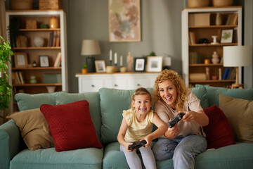 Mother and daughter playing video games at home