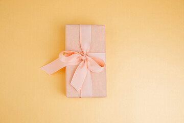 Greeting background. Gift wrapping in soft pink paper on a yellow background with copy space. Top view