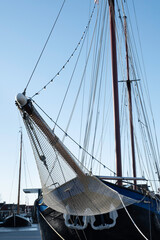 Ship's bow with jib boom and tightly knotted jib net in front of the foremast of a moored sailing...