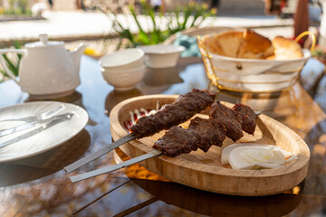 Lamb on wooden plate with kettle and tea cups. Oriental street food.