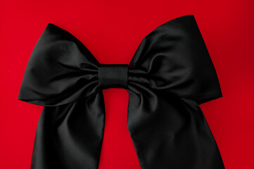 black bow on a red background. silk fabric, black satin. Fashion accessory 2024
