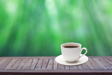 Coffee cup on wooden table with green background in blurred bokeh garden Relax.Vacation concept..