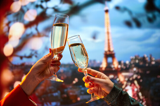 Fine dining restaurant in Paris marketing their terrace view and premium drinks. Female hands in dresses clinking champagne glasses over beautiful Parisian view. Holidays, celebration, events concept