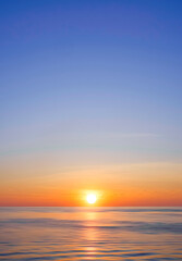 Idyllic natural sunrise sky background over sea in the morning with beautiful golden sunlight reflection on flowing water surface in vertical frame