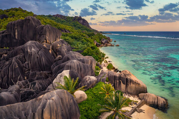 Aerial sunset view of Anse Source D'argent beach at the La Digue Island, Seychelles, with palm trees and amazing granite rock formations.