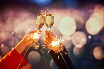 New Year. Male and female hands clinking champagne glasses over bokeh background. Making wishes,...