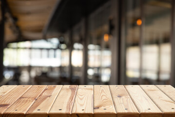 Empty wooden table in front of blurred cafe bar or restaurant. Abstract lights bokeh background, front view, free space for your product. High quality photo