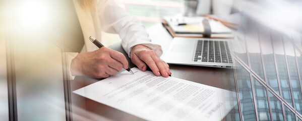 Hand of businesswoman signing a document (lorem ipsum text used); multiple exposure