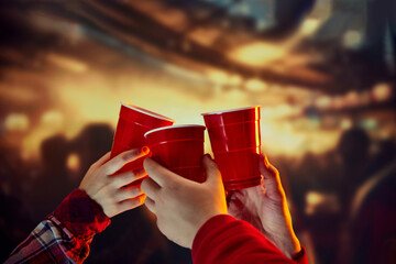 Group of friends meeting, clicking disposable plastic red cups over blurred background. Concept of holidays, celebration, events, friendship, leisure activity - obrazy, fototapety, plakaty