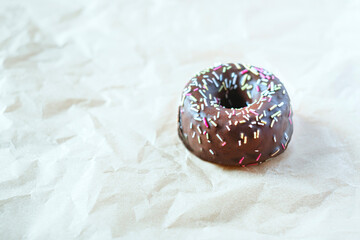 Sweet chocolate donut with sprinkles on light background, Delicious colorful chocolate donut