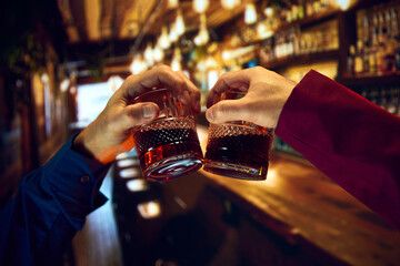 Male hands, businessmen clinking whiskey glasses, meeting at pub, restaurant. Friends meeting....