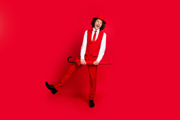 Full body photo of funky extravagant guy at prom party wear vintage classy outfit with parasol dance moves isolated on red color background © deagreez