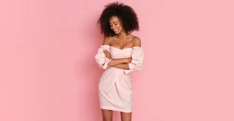 Foto op Canvas Beautiful afro american woman in a pink dress on a pink background. © forma82