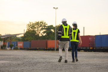 Male and Female engineers with geen safety jackets working at train station