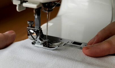Working on a modern sewing machine. Close-up of hands working on a sewing machine.