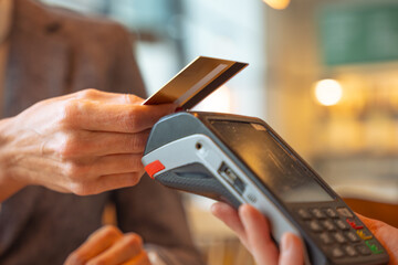 Woman customer paying with contactless credit card in a restaurant. 