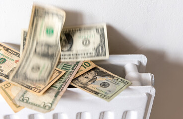 A heating, energy cost concept with a pile of US Dollars rising from a central heating radiator.