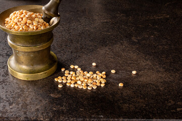 Vintage bronze mortar with peas on dark background for culinary concept