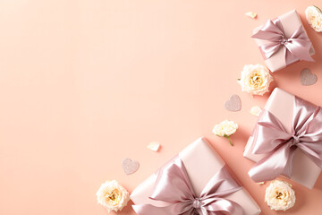 Gift boxes with ribbon bow and roses buds on pastel beige background. Top view photo for Happy Valentines day, Mothers day, International womens day concept.