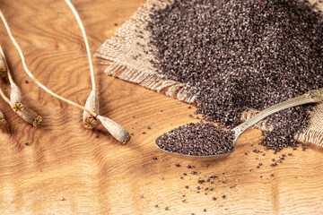 Close-up of poppy seeds and dried stalks on wooden background