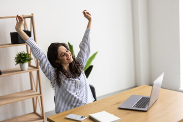 Happy excited woman at home workstation triumphing with raised hands