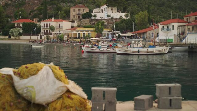 Medium establishing view of Leonidio Greece harbor with boats anchored and Mediterranean homes on hillside