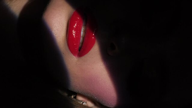 Beautiful model with bright makeup and red lips. Portrait of a girl close-up on a blue background. Vertical video.