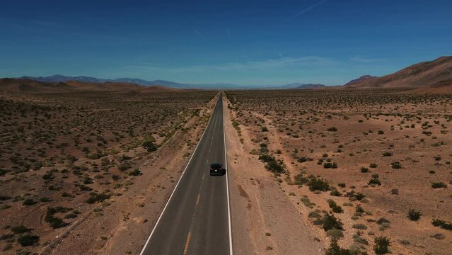 Modern car driving on desert highway in Nevada. Empty street to nowhere. Road from above in the dry hot Wild West America landscape. Aerial drone