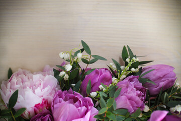 Pile of fresh pink tulips and lily of the valley on aged wooden table