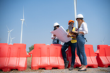 Group of engineers and architects on construction site with wind turbines in background