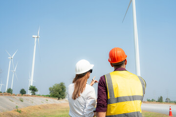 Back view of engineer and architect on construction site with wind turbines in background