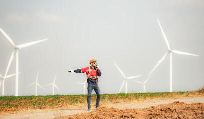 Engineer working in wind turbine farm with blue sky background