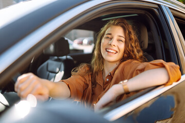 A happy woman is driving a car and smiling. Automobile travel. Sharing a car. Lifestyle concept.