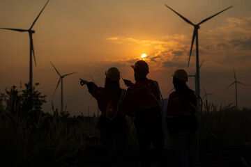 Silhouette of group engineers and windmills on the background of the setting sun