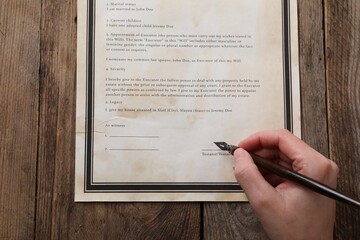 Woman signing Last Will and Testament at wooden table, top view