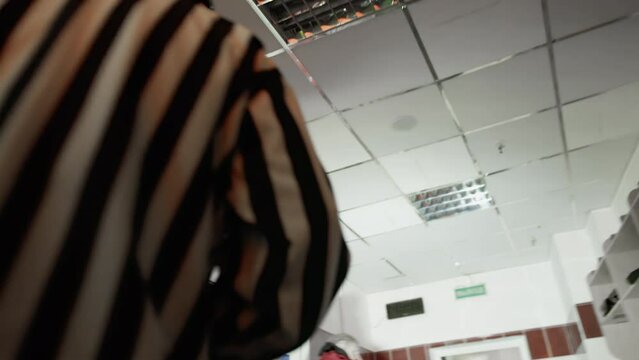 Hockey referee leaves the locker room for the ice arena. Dressing room indoor. Sportsmen change inside the checkroom