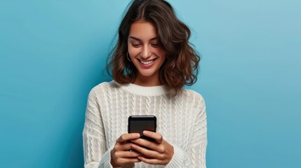Young adult smiling happy pretty latin woman holding mobile phone looking at smartphone, typing message doing ecommerce shopping on cell, using trendy apps on cellphone isolated on blue background