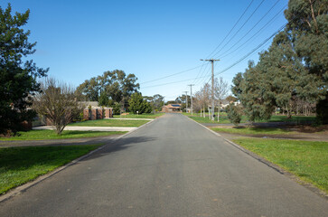 Fototapeta na wymiar Background texture of a low density suburban street or low traffic road with wide nature strips and some residential houses in the neighbourhood in a Melbourne's outer suburb. Werribee VIC Australia.
