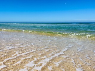 Blue seascape background, clear blue sky and blue sea horizon, sandy coastline