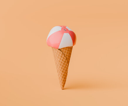 summer concept with a deflated beach ball like a scoop of ice cream atop a waffle cone on a peach-colored backdrop.