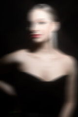 Make-up and fashion concept. Beautiful classic woman studio portrait. Model with classic hairstyle, fancy earrings, black dress and red lipstick. Model looking at camera. Motion blur effect style