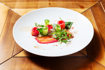 Red fish, salmon with cucumber and radish on a plate. Restaurant, cafe. On a wooden table.