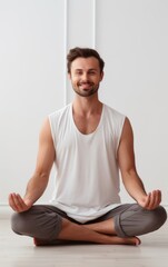 Obraz premium Happy handsome man sitting on floor in Lotus pose and meditating at home.