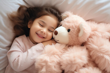 Top view of cute little preschooler girl lying cuddling with favorite fluffy toy waking up in cozy home bed