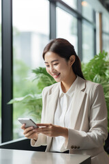 Fototapeta na wymiar Young busy happy Asian business woman manager using mobile cell phone tech in office
