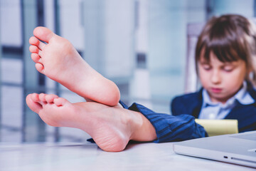 Business child girl working and resting at the same time. Selective focus on bare feet.